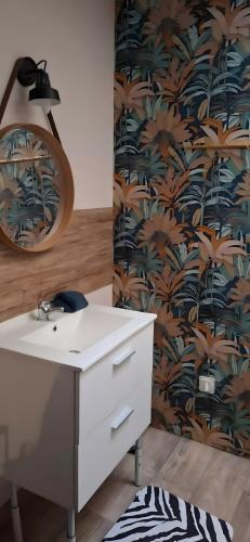 a bathroom with a white sink and a wallpaper with palm trees at Studios Saint dye sur Loire in Saint-Dyé-sur-Loire