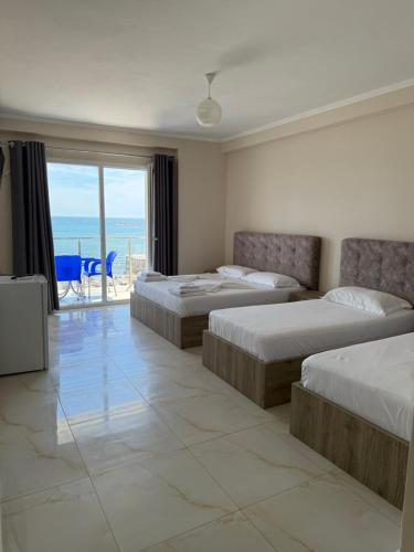 a bedroom with three beds and a view of the ocean at Hotel Fredi Shengjin in Shëngjin