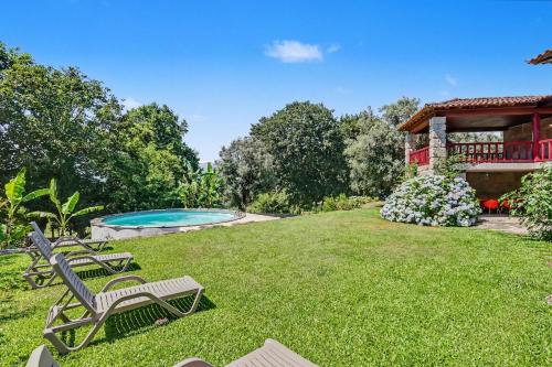 a yard with two chairs and a swimming pool at Casa Nova das Oliveiras in Verim