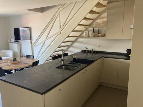 a kitchen with a sink and a table and stairs at ZEEZANDPAREL Westende-Bad Gezellig 3-slaapkamer appartement in Westende-Bad