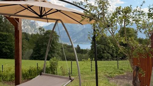 a swing with an umbrella in a field at Attersee Panorama Apartments in Steinbach am Attersee