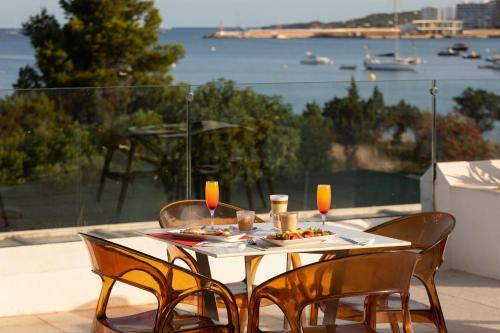 a table with a plate of food and two chairs at THB Naeco Ibiza - Adults Only in San Antonio Bay