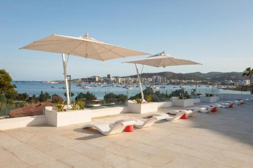 a row of white chairs and umbrellas on a roof at THB Naeco Ibiza - Adults Only in San Antonio Bay