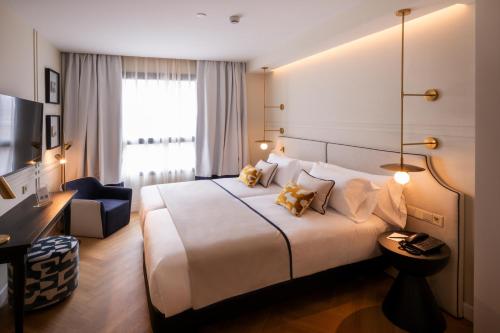 a hotel room with a large bed and a chair at Sercotel Sevilla Don Luciano in Seville