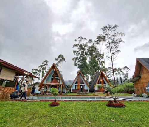 a group of houses with trees in the background at Cozzy Artana Cabin in Palayangan