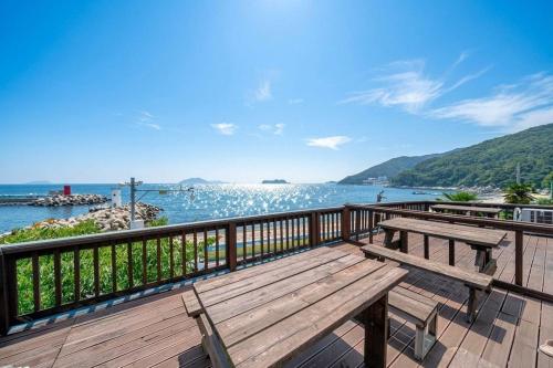 a wooden bench sitting on a deck overlooking the water at Namhae Padosori Oceanview Pension in Namhae
