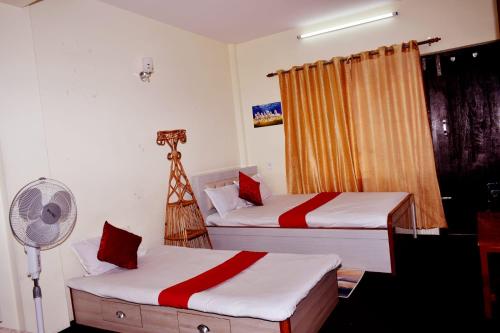 a room with two beds and a fan in it at Kattel Homestay and Apartments in Bālāju