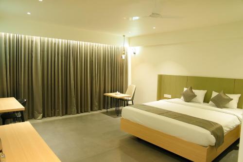 a bedroom with a bed and a table and a desk at Hotel The Nature Regency in Satara