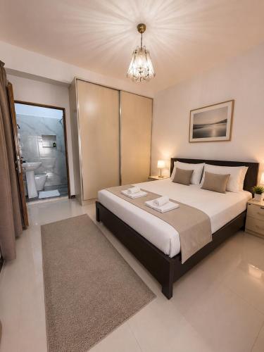 a bedroom with a large bed and a chandelier at Drasa Harmony Apartment in Gjirokastër