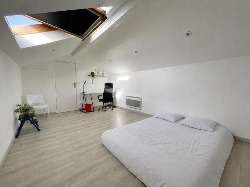 a white bedroom with a large bed and a desk at Grande Chambre avec parking possible en supplément, BORDEAUX BASTIDE in Bordeaux