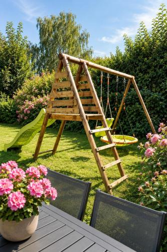 a wooden swing in a garden with pink flowers at Au Charme De Bussy - Maison proche Disney avec terrasse et parking in Bussy-Saint-Georges