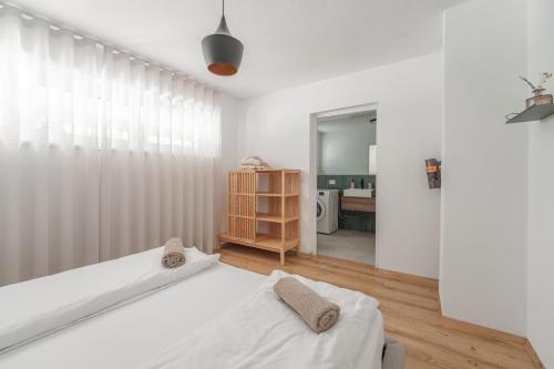 a white bedroom with two beds and a bathroom at Mountain View Suites in Tesimo