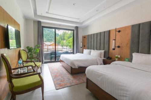 a hotel room with two beds and a balcony at Luxus Naran in Naran