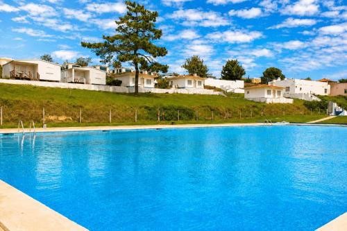 a large blue swimming pool with houses in the background at Kampaoh Praia do Meco in Sesimbra
