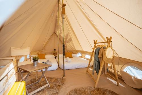 a tent with a bed and a table in it at Kampaoh Praia do Meco in Sesimbra