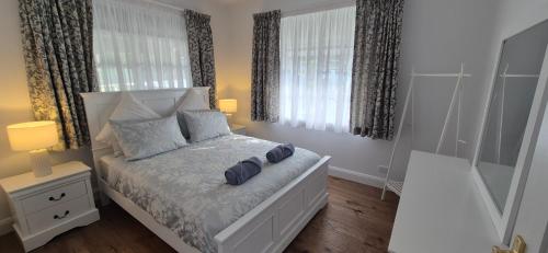 a white bedroom with a bed with two pillows at Elegant White Cottage in Bomaderry