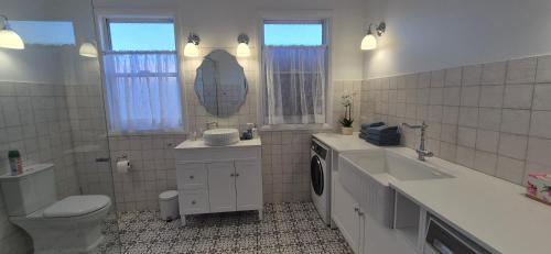 a bathroom with a toilet and a sink and a mirror at Elegant White Cottage in Bomaderry