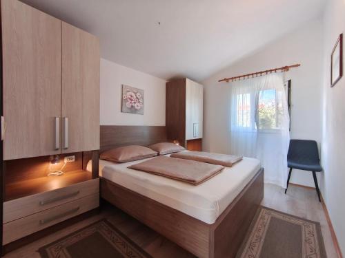 a bedroom with a bed and a chair in it at Apartmani Katarina&Ivan Krstinić in Rab