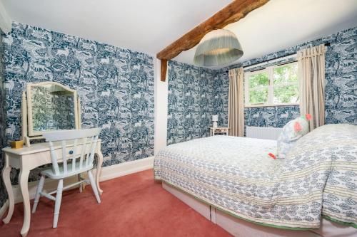 a bedroom with blue wallpaper and a bed and a desk at The Cottage at Cobbolds Mill in Monks Eleigh
