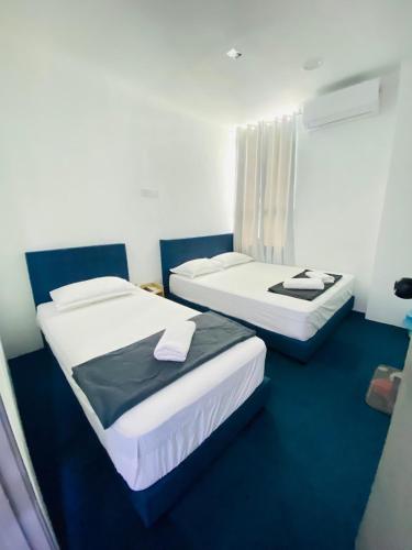 two beds in a small room with blue carpet at Enviropath Hotel now Bayan Nur Inn in Kampong Pengkalan