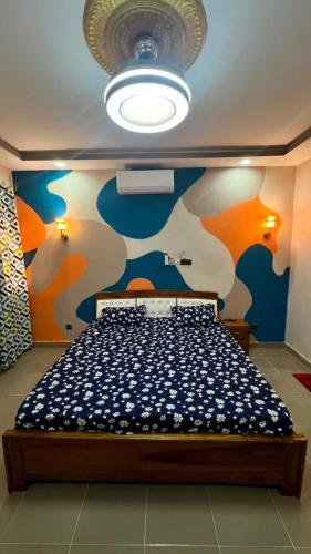 ein Schlafzimmer mit einem Bett und einer blau-orangenen Wand in der Unterkunft Résidence AELA in Banfora