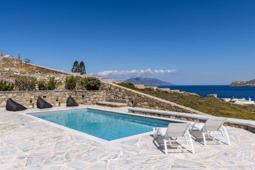a swimming pool with two chairs and the ocean at Lunar Villa in Glastros