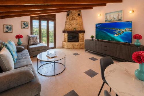 a living room with a tv and a fireplace at Aliston Hotel Thassos in Skala Potamias