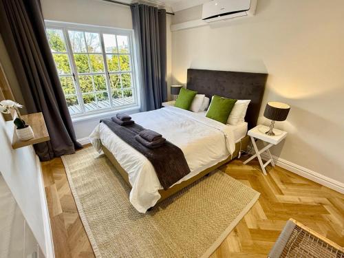 a bedroom with a bed with green pillows and a window at Anesta House in Stellenbosch