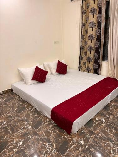 a bed with red pillows on it in a room at TAG Farm in Greater Noida