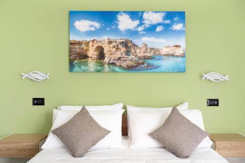 a bed with white pillows and a painting on the wall at Piazza Pertini Rooms in Melendugno