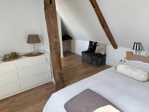 a bedroom with a white bed and wooden beams at La clé du Temps in Falaise