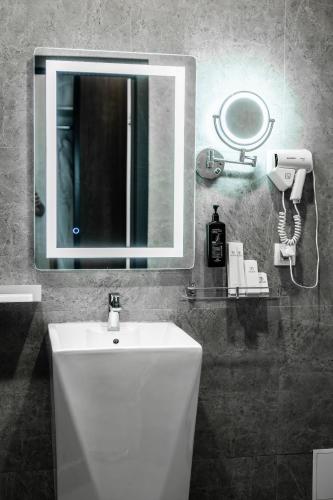 a bathroom with a white sink and a mirror at Dostyk Mildom Almaty in Almaty