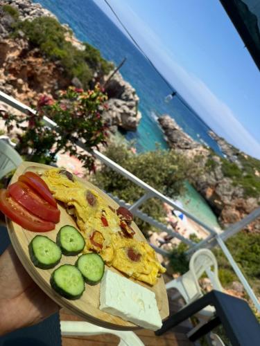 a person holding a plate with a slice of pizza and vegetables at Camping Aquariumm in Himare