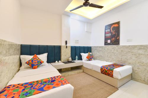 a bedroom with two beds and a ceiling fan at FabHotel Metro Residency, Indore Junction Railway Station in Indore