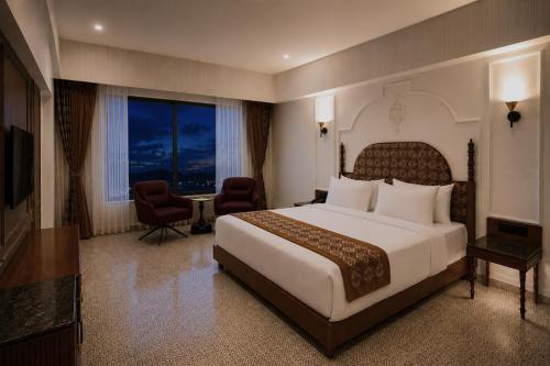 a hotel room with a large bed and a large window at Haldi Kumkum Resort in Limodra