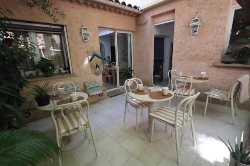 a patio with white tables and chairs and windows at Boutique Hôtel Azur in Marseille