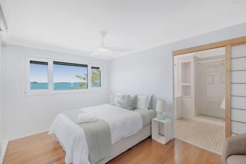 a white bedroom with a bed and a window at Silver Waters | Private Cove | Ocean Views in Zilzie