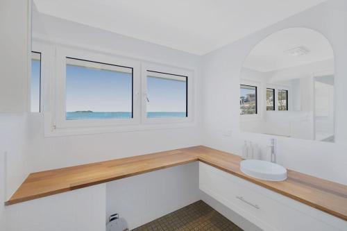 a white bathroom with a sink and two windows at Silver Waters | Private Cove | Ocean Views in Zilzie