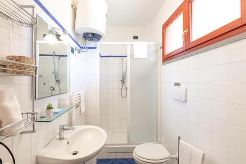 a white bathroom with a sink and a toilet at Villa La Cavaliera in San Vincenzo