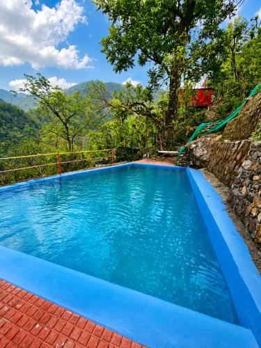 a blue swimming pool with mountains in the background at Shivpuri Ghumakkad Resort in Shivpuri