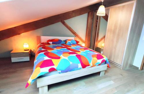a bed with a colorful comforter in a bedroom at Le moulin de la hamelle in Yoncq