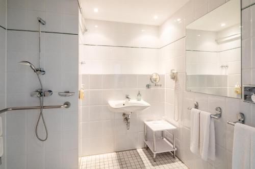 a white bathroom with a sink and a shower at ABACUS Tierpark Hotel in Berlin