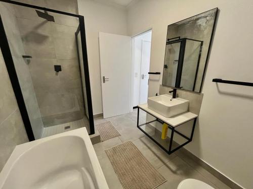 un baño con bañera, lavabo y espejo en Comfy 1 Bed 1 Bath En-Suite, en Chartwell