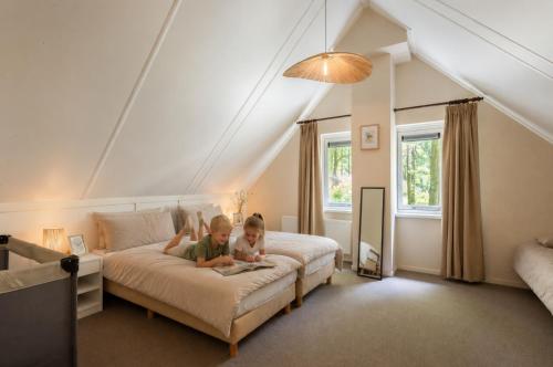 two children are sitting on a bed in a bedroom at Bospark Garderen in Garderen