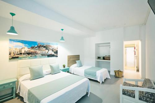 two beds in a room with white walls at Hostal Sunset Ibiza in San Antonio