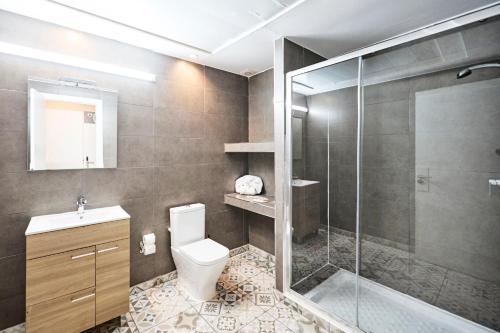 a bathroom with a toilet and a glass shower at Hostal Sunset Ibiza in San Antonio