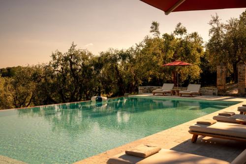 a swimming pool with lounge chairs and an umbrella at Fattoria di Vegi in Castellina in Chianti
