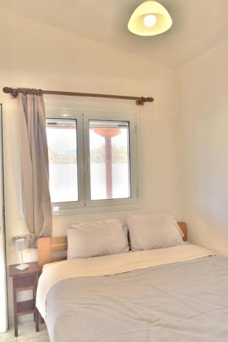 a bedroom with a bed and two windows at Small farmhouse by M in Egina