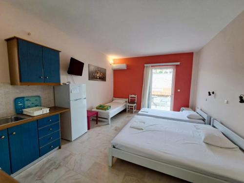 a room with two beds and a kitchen with a refrigerator at Areti & Maria Apartments in Gythio