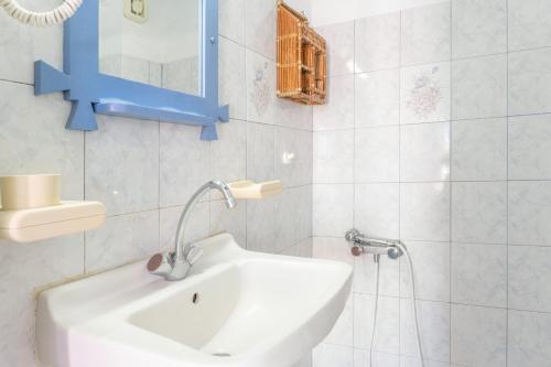 a white bathroom with a sink and a blue mirror at Agnadi Apartment in Serifos Chora